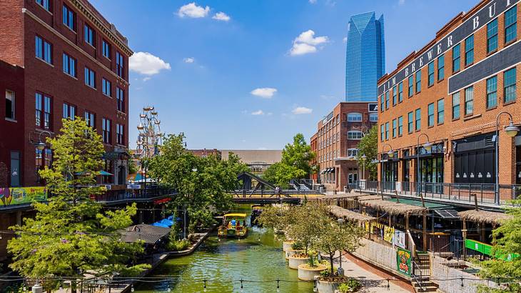 A river with trees and red brick buildings on either side and a modern skyscraper