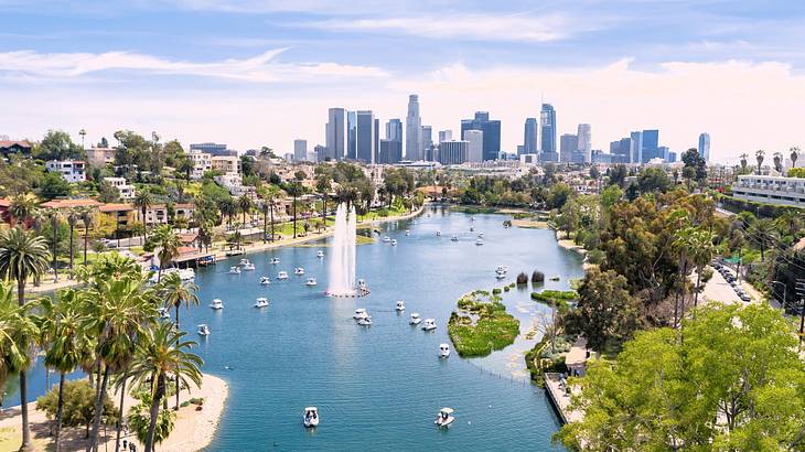 An artificial lake with small boats and a fountain with a city skyline next to it