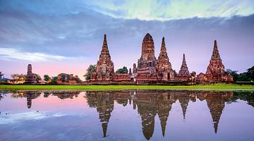 Ancient temples and shrines reflected in water against a colourful sky