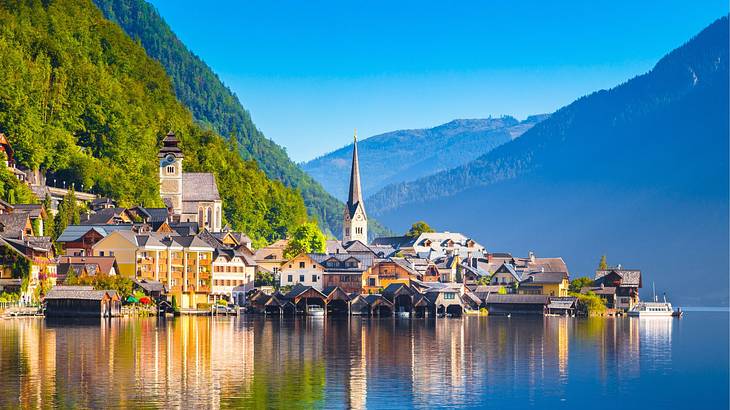 A lake next to greenery-covered hills and a small village with houses and a church