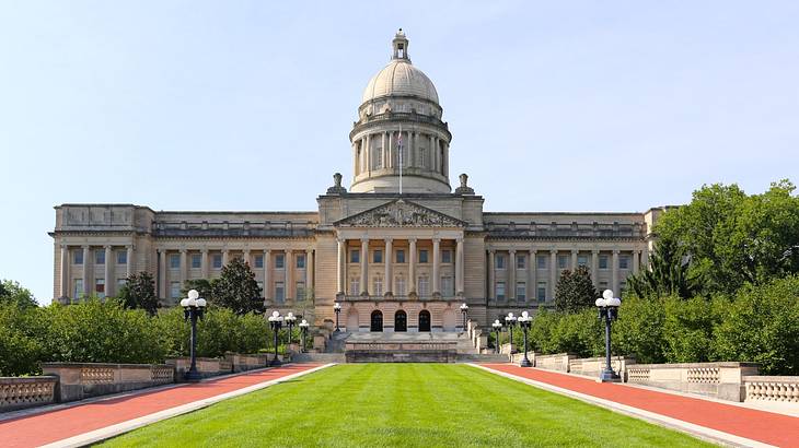 A large stone building with a dome next to grass and trees