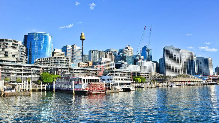 A port with docked ships near skyscrapers and buildings on a sunny day