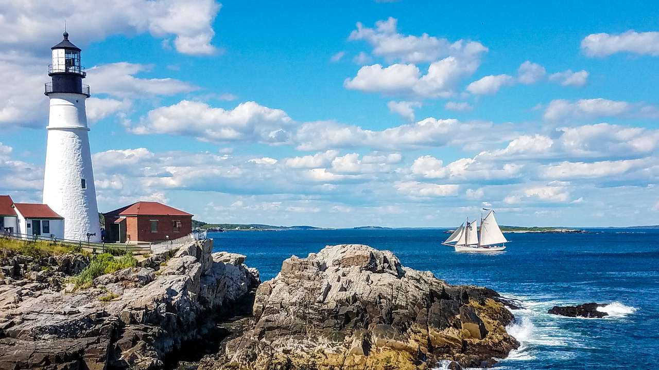 A lighthouse on a rocky headland near the sea with a ship on it