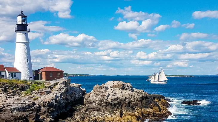 A lighthouse on a rocky headland near the sea with a ship on it