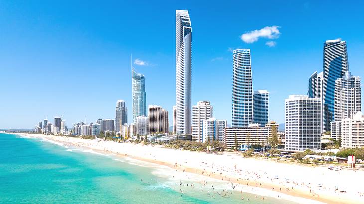 Panorama of a beautiful skyline with tall buildings along blue water and white sand