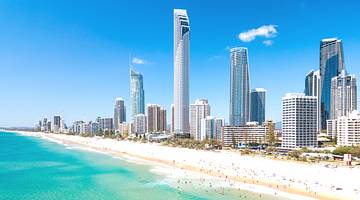 Panorama of a beautiful skyline with tall buildings along blue water and white sand
