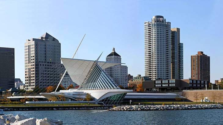 City buildings and a modern white structure near a body of water