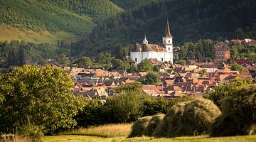 Transylvania itinerary - A church in between homes and green rolling hills, Sibiu Transylvania itinerary - A church in between homes and green rolling hills, Sibiu