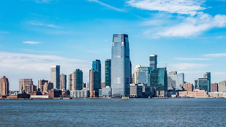 A city skyline near a body of water under a blue sky with some cloud