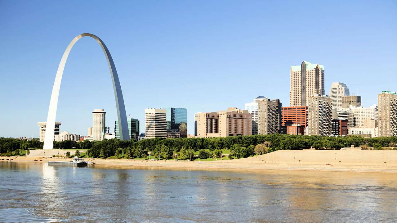 Buildings and a large arch structure near a body of water