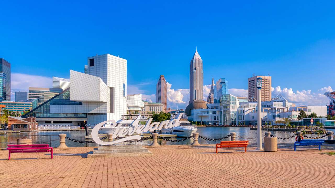 A boardwalk with a "Cleveland" sign and the city skyline in the background