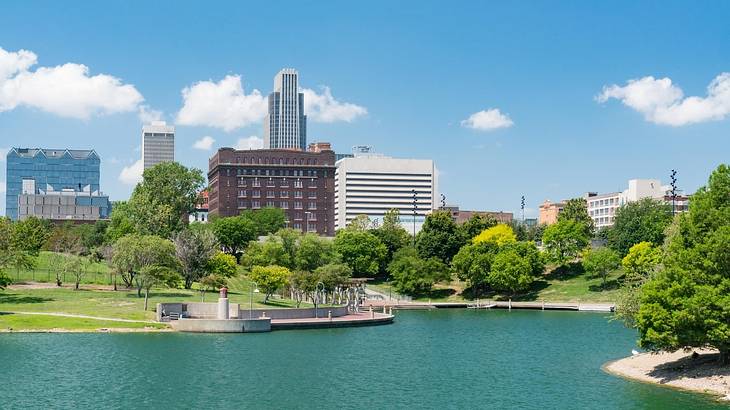 A city skyline with a lake and trees in front of it on a clear day