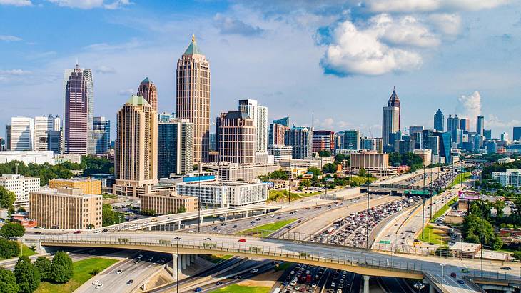 Skyscrapers on a skyline with a highway in front of them under a blue sky with clouds