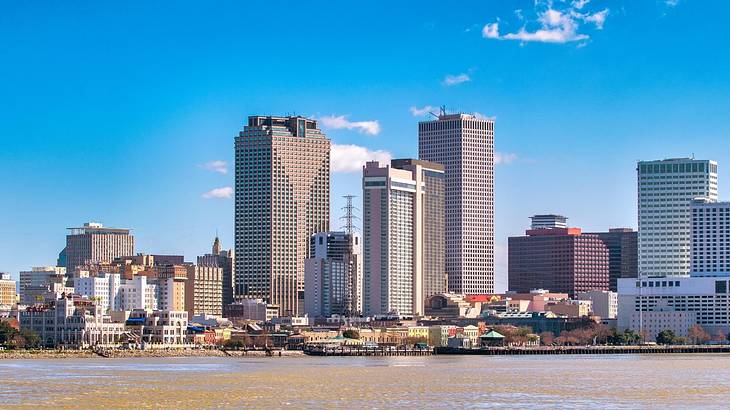 A skyline of tall buildings overlooking water, under a blue sky with a few clouds