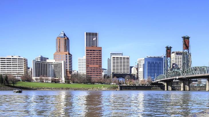 A city skyline with a lake in front and a bridge over the water on a clear day