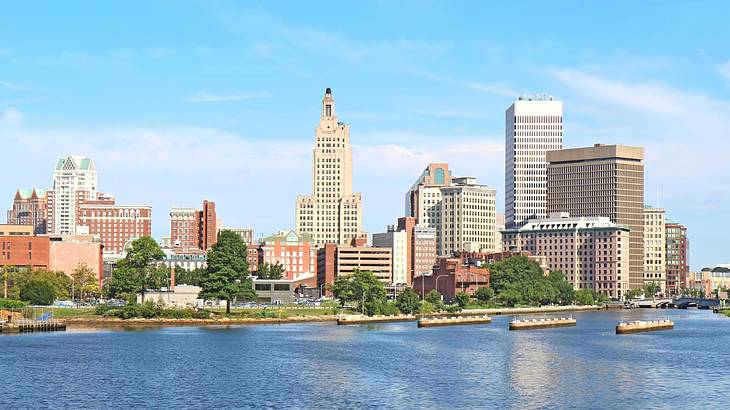 A skyline with tall buildings and a river in front of it under a blue sky