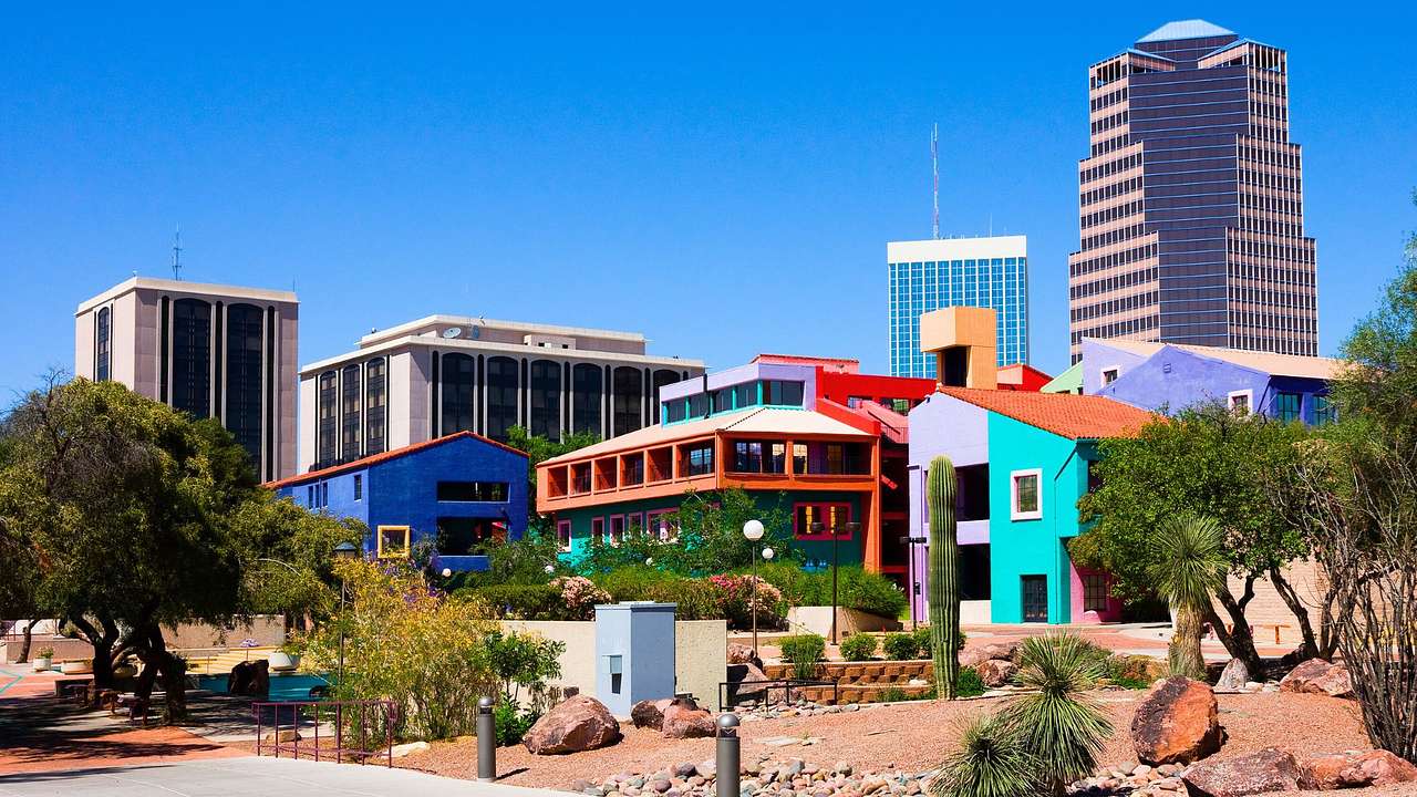 Colorful adobe buildings next to a tall tower and greenery under a blue sky