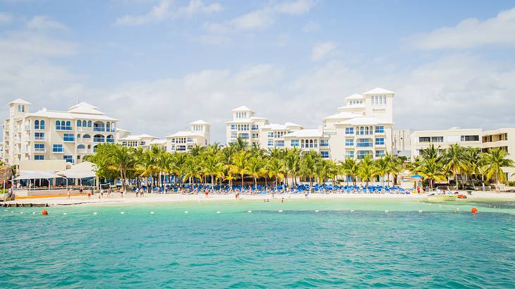 Blue ocean with a beach, tourist hotel and resort, and palm trees on the shore