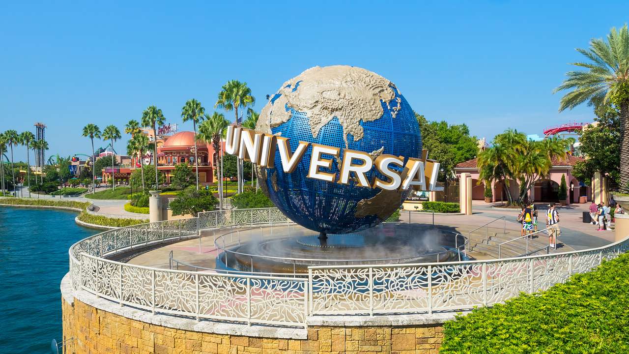 A globe structure that says "Universal" on a circular balcony next to a lake