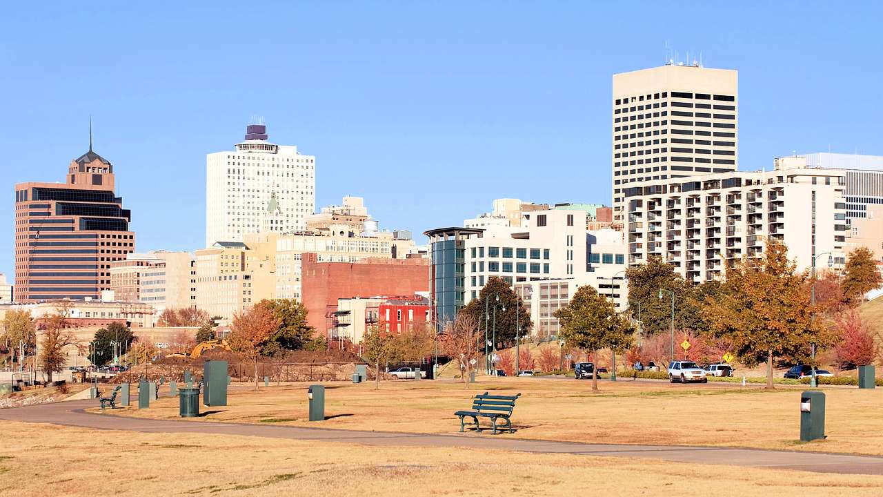 City buildings near a park with benches during the fall