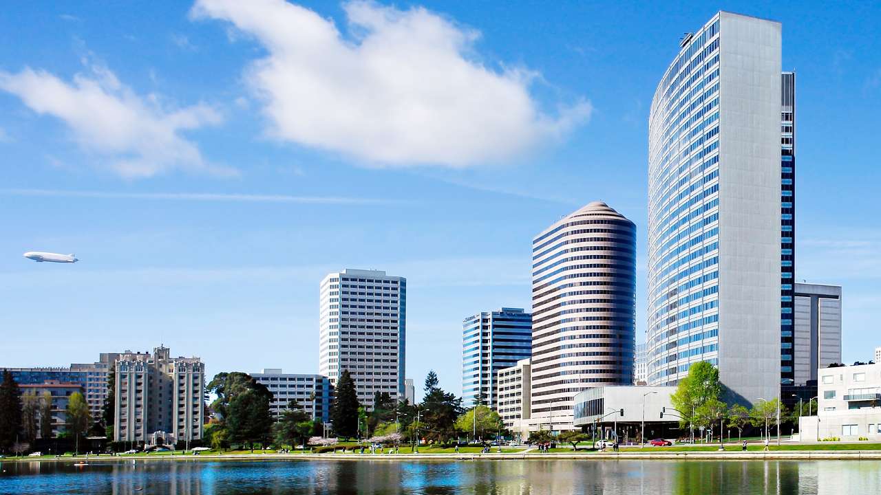 Modern city buildings next to a lake and a blue sky with clouds