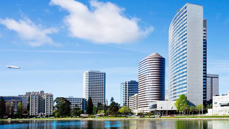 Modern city buildings next to a lake and a blue sky with clouds