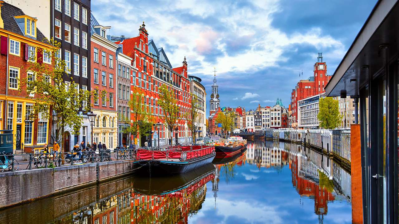 Colorful buildings line a canal with boats tied to it, on a partly cloudy day