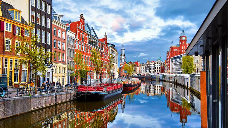 Colorful buildings line a canal with boats tied to it, on a partly cloudy day