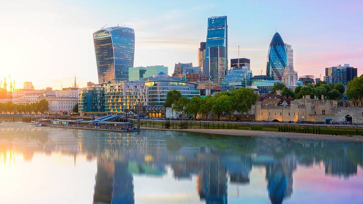 Tall glass city buildings reflected in a river at dusk Tall glass city buildings reflected in a river at dusk