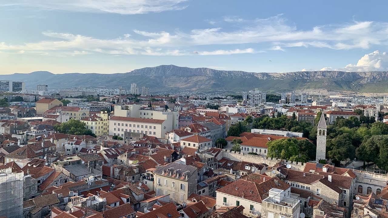 Looking over building rooftops in a historic centre with mountains at the back