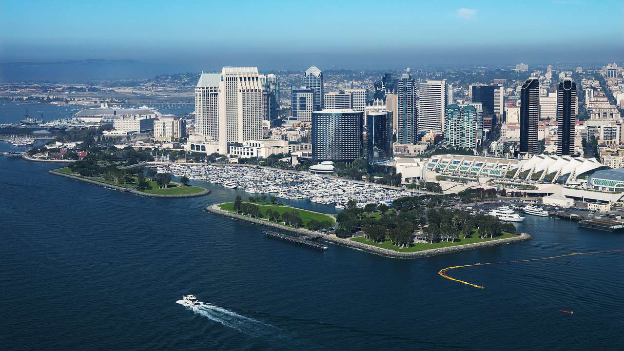 Aerial of boats near a shoreline with tall and modern skyscrapers on a sunny day