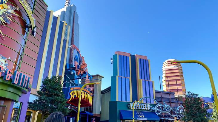 People walking near colorful movie-themed buildings under a clear blue sky