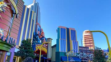 People walking near colorful movie-themed buildings under a clear blue sky