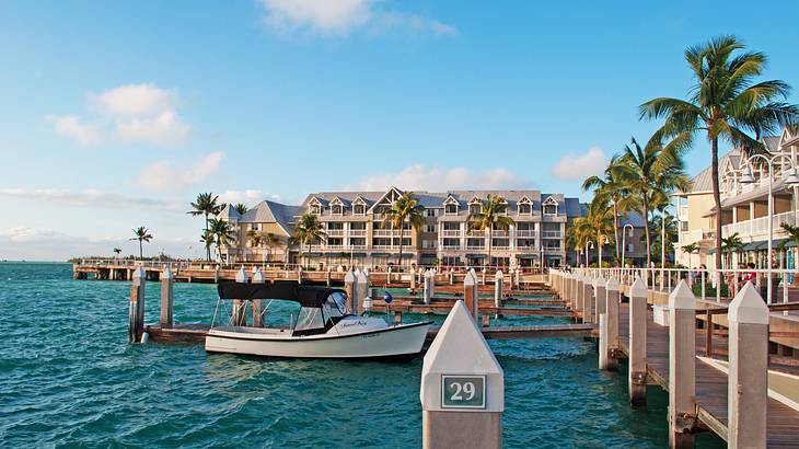 Oceanside houses with a pier in front of them, next to water with a boat on it