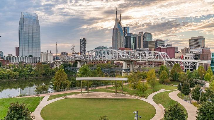 The Nashville skyline with skyscrapers and a green park and bridge in front of it