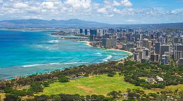 A view of turquoise ocean with green space and cityscape on the shore