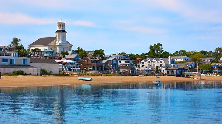 A quaint seaside town with a sandy shore and ocean water in front of it