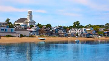 A quaint seaside town with a sandy shore and ocean water in front of it