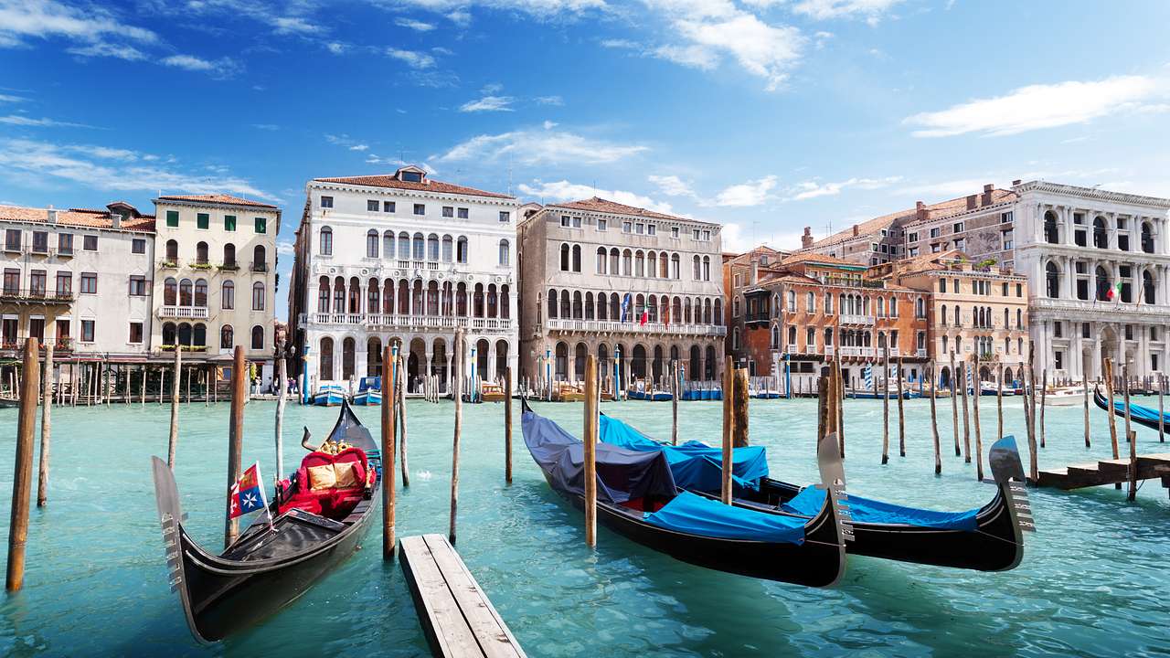 Gondolas parked at a little pier, with Venetian-style buildings in the distance