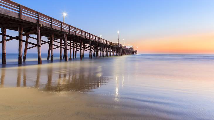 Sunset over a lighted wooden pier overlooking a calm beach