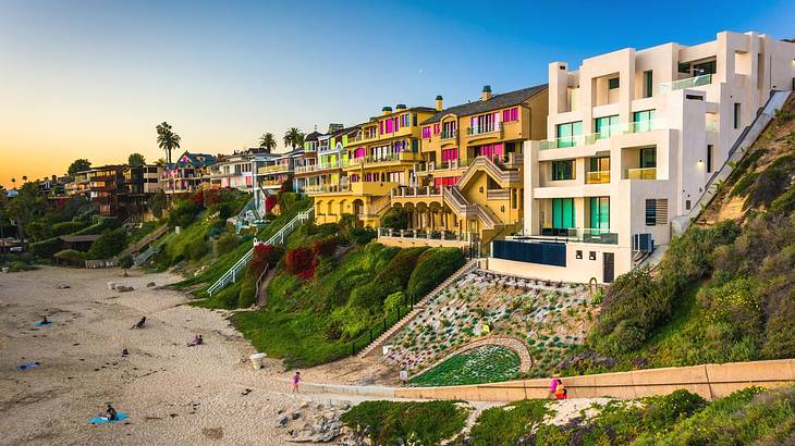 Looking towards a beach against a building and grass-filled cliff on a nice day