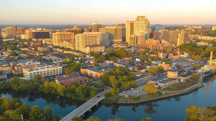 An aerial of a river flowing by a town with buildings under an evening sky