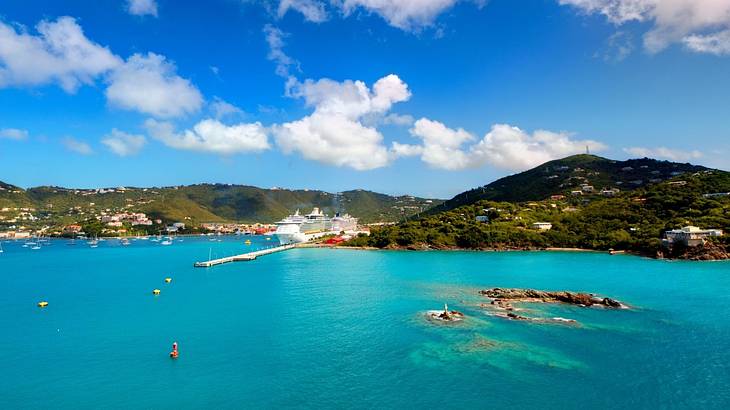 Turquoise water with green cliffs surrounding it and boats docked near the shore