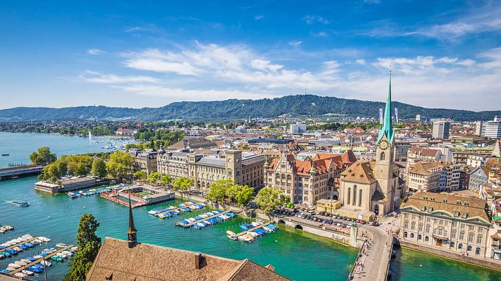 An aerial view of a town with historical buildings, water, and a green mountain