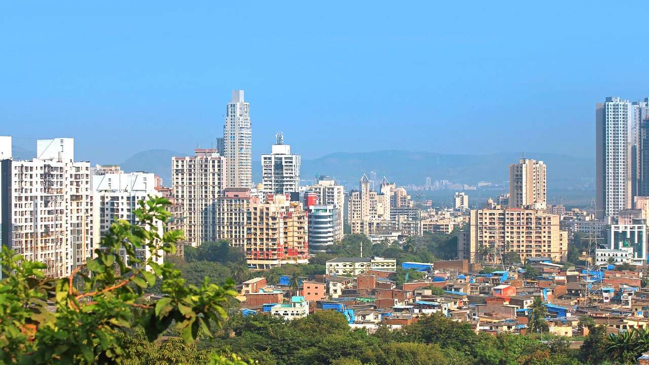 A skyline with tall skyscrapers overlooking a suburb surrounded by green trees