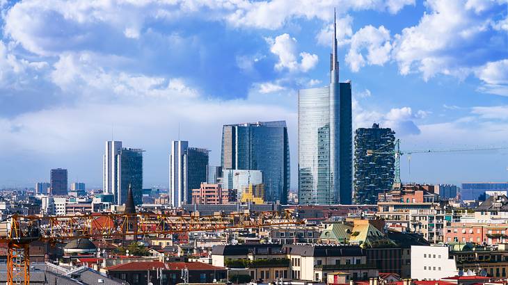 A downtown skyline overlooking small multi-coloured buildings under a cloudy sky