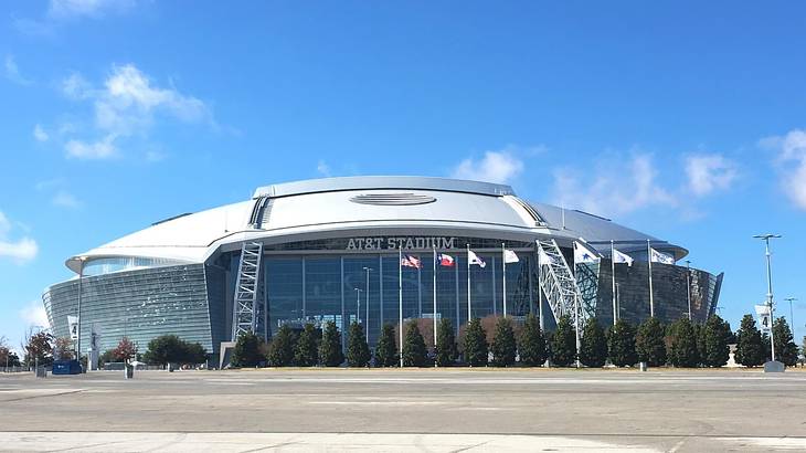 A football stadium with a sign that says "AT&T Stadium" and flags in front of it