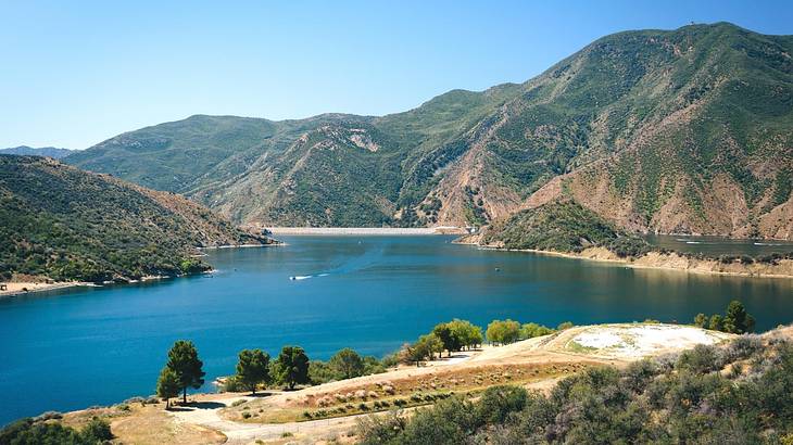 A lake with greenery and greenery-covered mountains surrounding it A lake with greenery and greenery-covered mountains surrounding it