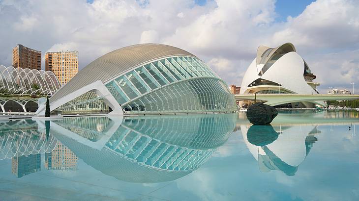 Modern white and glass half domes reflected into a human-made shallow pool