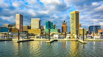 The Baltimore skyline with city buildings next to water with a boat dock on it